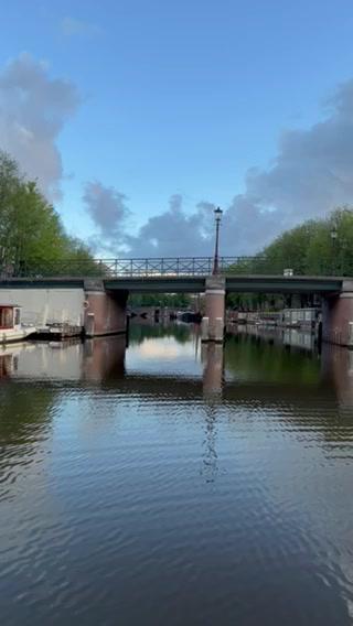 A serene canal scene with a bridge and trees on a sunny afternoon